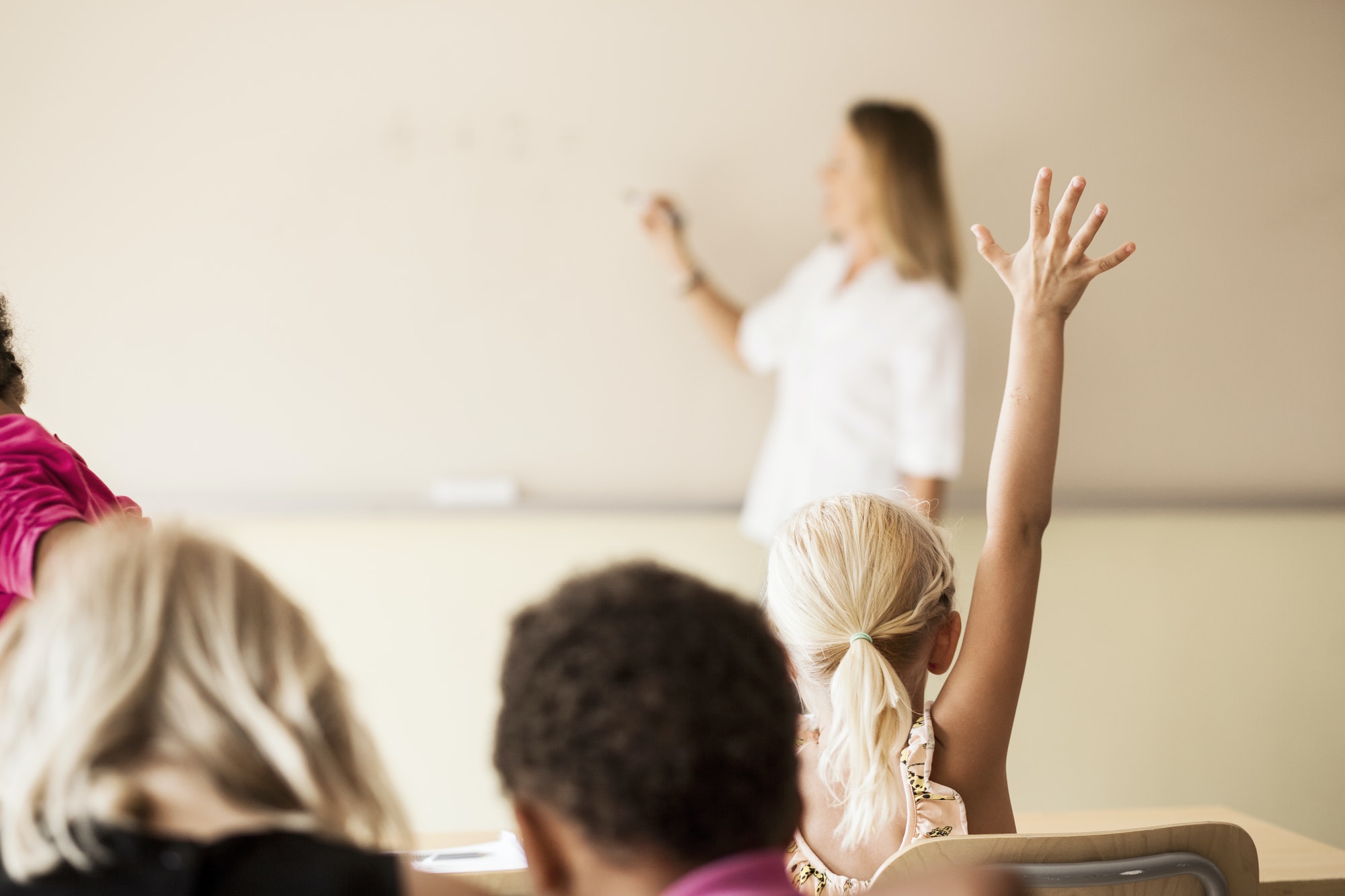 Mature teacher teaching mathematics to children in classroom